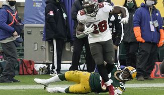 Tampa Bay Buccaneers&#39; Leonard Fournette (28) evades a tackle by Green Bay Packers&#39; Adrian Amos to score on a 20-yard touchdown run during the first half of the NFC championship NFL football game in Green Bay, Wis., Sunday, Jan. 24, 2021. (AP Photo/Morry Gash)