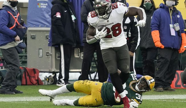 Tampa Bay Buccaneers&#x27; Leonard Fournette (28) evades a tackle by Green Bay Packers&#x27; Adrian Amos to score on a 20-yard touchdown run during the first half of the NFC championship NFL football game in Green Bay, Wis., Sunday, Jan. 24, 2021. (AP Photo/Morry Gash)