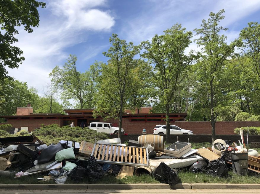 Piles of household debris line Valley Drive in Midland, Michigan, on Wednesday, May 27, 2020. The Michigan Dam Safety Task Force on Wednesday, Feb. 3, 2021 delayed sending the governor its final recommendations, which include increased monitoring of dams and other risk reduction measures. (AP Photo/Tammy Webber, file)