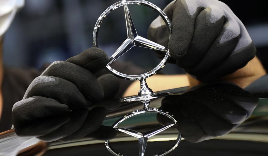 FILE - In this Thursday, April 30, 2020 file photo, an employee attaches a Mercedes emblem as he works on a Mercedes-Benz S-class car at the Mercedes plant in Sindelfingen, Germany. German automaker Daimler said it will split itself into two independent companies by spinning off its truck and bus division. The Stuttgart-headquartered company said Wednesday, Feb. 3, 2021 that a significant majority stake in the truck business would be distributed to current shareholders, and that Daimler would “at the appropriate time” be renamed Mercedes-Benz, the brand name under which it sells luxury cars.  (AP Photo/Matthias Schrader, file)