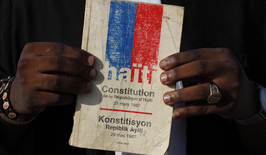 FILE - In this Oct. 8, 2019 file photo, entrepreneur and youth leader Pascéus Juvensky St. Fleur, 26, holds up his copy of the Haitian constitution during an interview in Port-au-Prince, Haiti. Haiti has unveiled multiple proposed changes to overhaul the country’s Constitution that officials plan to present to voters starting in Feb. 2021 for an upcoming referendum that looms amid growing unrest. (AP Photo/Rebecca Blackwell, File)