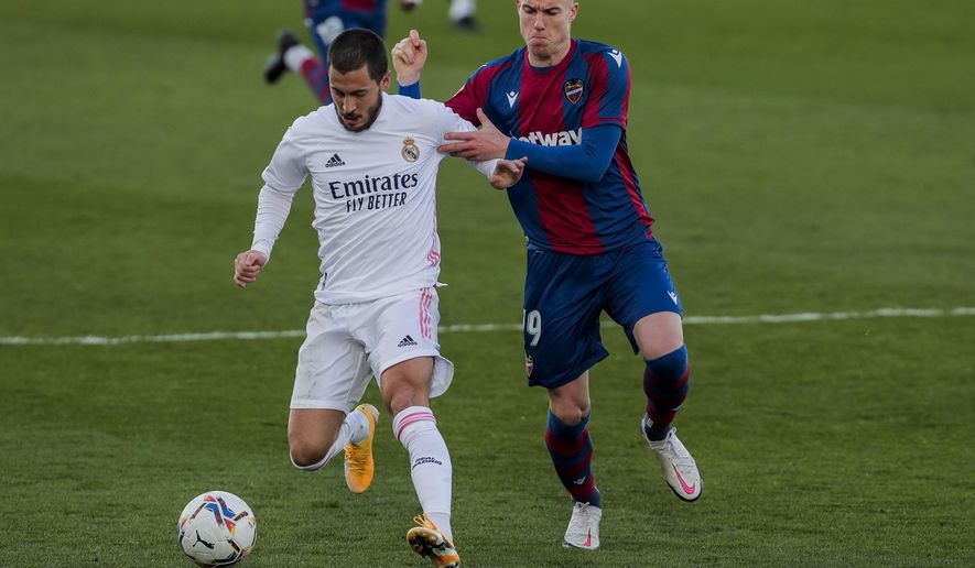 Real Madrid's Eden Hazard, left, duels for the ball with Levante's Roger Marti during the Spanish La Liga soccer match between Real Madrid and Levante at the Alfredo Di Stefano stadium in Madrid, Spain, Saturday, Jan. 30, 2021. (AP Photo/Manu Fernandez)