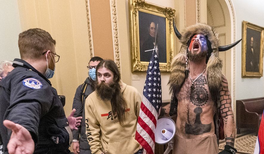 In this Wednesday, Jan. 6, 2021, file photo, supporters of President Donald Trump, including Jacob Chansley, right with fur hat, are confronted by U.S. Capitol Police officers outside the Senate Chamber inside the Capitol in Washington. (AP Photo/Manuel Balce Ceneta, File)