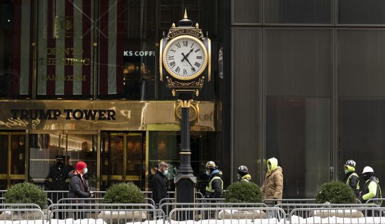 People walk between police barricades in front of Trump Tower, Wednesday, Feb. 3, 2021, in New York. Former President Donald Trump owns a penthouse condominium in the skyscraper and the Trump Organization has its headquarters here. (AP Photo/Mark Lennihan)