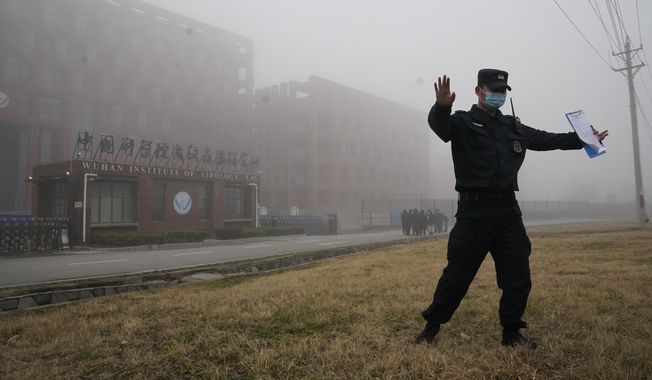 A security official moves journalists away from the Wuhan Institute of Virology after a World Health Organization team arrived for a field visit in Wuhan in China&#x27;s Hubei province on Wednesday, Feb. 3, 2021. The WHO team is investigating the origins of the coronavirus pandemic has visited two disease control centers in the province. (AP Photo/Ng Han Guan) **FILE**