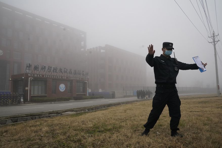 A security official moves journalists away from the Wuhan Institute of Virology after a World Health Organization team arrived for a field visit in Wuhan in China&#39;s Hubei province on Wednesday, Feb. 3, 2021. The WHO team is investigating the origins of the coronavirus pandemic has visited two disease control centers in the province. (AP Photo/Ng Han Guan) **FILE**