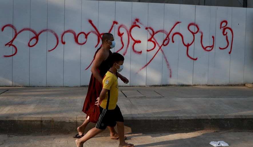 Pedestrians pass by a graffiti reading as &amp;quot;don&#39;t want dictatorship&amp;quot; in Yangon, Myanmar, Tuesday, Feb. 4, 2021. Myanmar&#39;s new military government has blocked access to Facebook as resistance to Monday&#39;s coup surged amid calls for civil disobedience to protest the ousting of the elected civilian government and its leader Aung San Suu Kyi. (AP Photo)