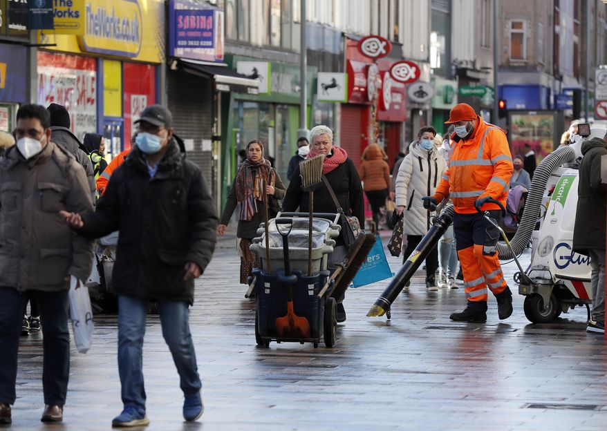 Road cleaners work in the town centre of Ilford in London, Friday, Jan. 29, 2021. In parts of east London, the pandemic is hitting much harder than most places in the U.K. The borough of Redbridge had the nation's second worst infection rate in January, with an estimated 1 in 15 residents thought to be infected. (AP Photo/Frank Augstein)
