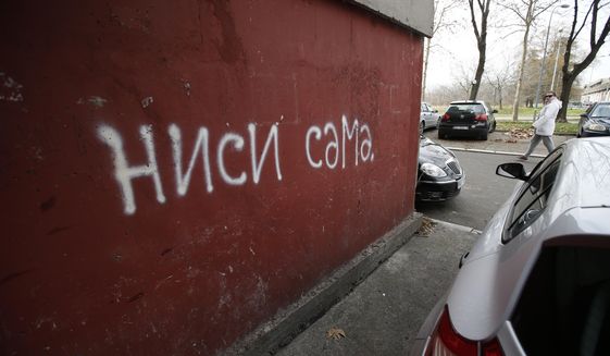 In this photo taken Thursday, Jan. 28, 2021, a woman walks past a &amp;quot;Nisi sama&amp;quot;, which means &amp;quot;You are not alone&amp;quot; slogan, in Belgrade, Serbia. A #MeToo-like movement is sweeping the strongly patriarchal Western Balkans and activists hope there will be no turning back. (AP Photo/Darko Vojinovic)