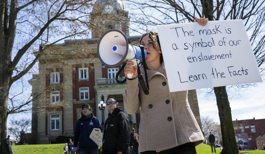 Rachel Powell, of Sandy Lake, Pa., uses a bullhorn to talk to passing cars while protesting stay-at-home orders and the shutdown of non-essential businesses due to the coronavirus pandemic outside the Mercer County Courthouse, on April 20, 2020, in Mercer, Pa. Federal agents on Thursday, Feb. 4, 2021, were at the home of Powell, who told a magazine this week she was at the U.S. Capitol last month during the riot by supporters of then-President Donald Trump, a TV station reported. WKBN-TV said investigators were conducting court-authorized activity at her home. (Tanner Mondok/The Herald via AP)
