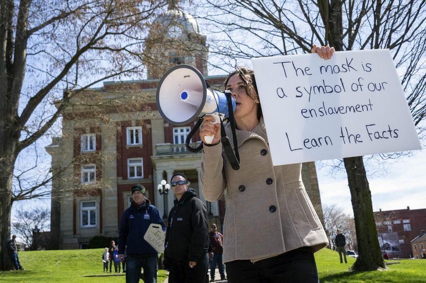 Rachel Powell, of Sandy Lake, Pa., uses a bullhorn to talk to passing cars while protesting stay-at-home orders and the shutdown of non-essential businesses due to the coronavirus pandemic outside the Mercer County Courthouse, on April 20, 2020, in Mercer, Pa. Federal agents on Thursday, Feb. 4, 2021, were at the home of Powell, who told a magazine this week she was at the U.S. Capitol last month during the riot by supporters of then-President Donald Trump, a TV station reported. WKBN-TV said investigators were conducting court-authorized activity at her home. (Tanner Mondok/The Herald via AP)