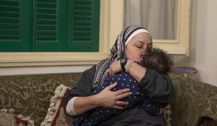Foster mother Yasmina El Habbal kisses with her 7-month-old daughter Ghalia, at their apartment in Cairo, Egypt, Wednesday, Jan. 20, 2021. Egyptians who have taken in children under the Islamic system of guardianship known as Kafala are turning to social media to raise awareness as part of a push to provide orphans with permanent families. (AP Photo/Nariman El-Mofty)