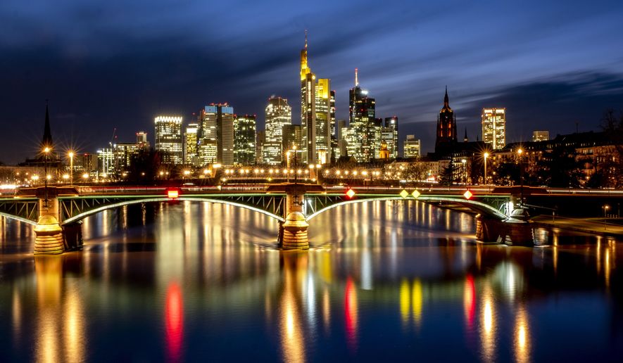 Lights of the city are reflected in the river Main in Frankfurt, Germany, Thursday, Feb. 4, 2021. In background the buildings of the banking district. (AP Photo/Michael Probst)