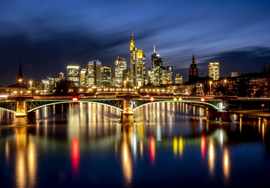 Lights of the city are reflected in the river Main in Frankfurt, Germany, Thursday, Feb. 4, 2021. In background the buildings of the banking district. (AP Photo/Michael Probst)