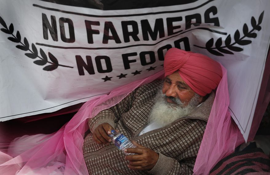 FILE - In this Monday, Dec. 14, 2020, file photo, a protesting farmer rests on his tractor trailer blocking a highway with other farmers at the Delhi- Haryana border, on the outskirts of New Delhi, India. As the farmers camp out at the edges of the capital, protesting new agricultural laws they say will devastate their earnings, the mainstream and social media have come under unprecedented attacks from Prime Minister Narendra Modi’s Bharatiya Janata Party. Critics say it has used the massive demonstrations to escalate a crackdown on free speech, detaining journalists and freezing Twitter accounts. (AP Photo/Manish Swarup, File)