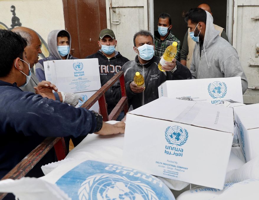 In this March 31, 2020 file photo, Palestinian workers load food supplies distributed by the United Nations Relief and Works Agency (UNRWA) at the Sheikh Redwan neighborhood of Gaza City.   (AP Photo/Adel Hana, File)  **FILE**