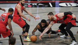 Brooklyn Nets&#39; Kyrie Irving, center, fights for control of the ball with Toronto Raptors&#39; Aron Baynes (46) and Fred VanVleet (23) during the second half of an NBA basketball game Friday, Feb. 5, 2021, in New York. (AP Photo/Frank Franklin II)