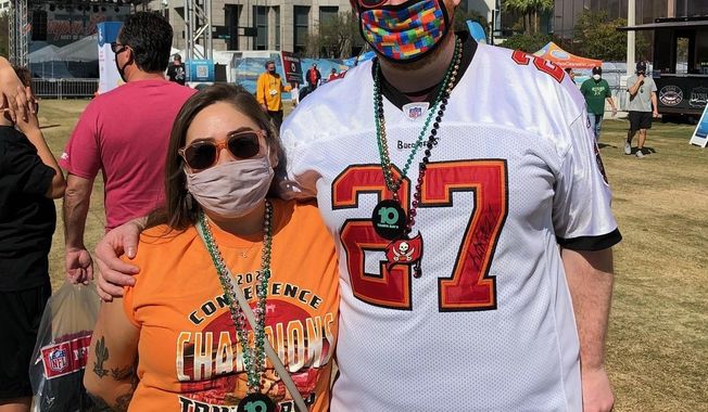 Craig Cathers, right, of Minneapolis, and Coreana Fairbanks, also of Minneapolis, pose for a photo while attending the NFL Super Bowl Experience theme park in downtown Tampa, Fla., Friday, Feb. 5, 2021. (AP Photo/Dennis Waszak Jr.)