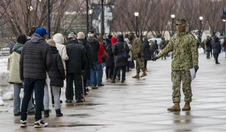 A member of the National Guard gives people direction standing in line at a COVID-19 vaccination site at Yankee Stadium, Friday, Feb. 5, 2021, in the Bronx borough of New York. Yankee Stadium opened as a COVID-19 vaccination site Friday, drawing lines of people from surrounding neighborhoods in the Bronx. The mega-site is being restricted to Bronx residents as a way to boost vaccination rates in the New York City borough with the highest percentage of positive coronavirus test results. (AP Photo/Mary Altaffer)