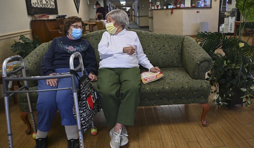 Carmela Sileo, left, and Susan McEachern sit next to each other and talk in the dayroom Wednesday, Feb. 3, 2021, at Arbor Springs Health and Rehabilitation Center in Opelika, Ala. Coronavirus cases have dropped at U.S. nursing homes and other long-term care centers over the past few weeks, offering a glimmer of hope that studies and health officials link to various factors, including the start of vaccinations, the easing of a post-holiday virus surge and better prevention. (AP Photo/Julie Bennett)