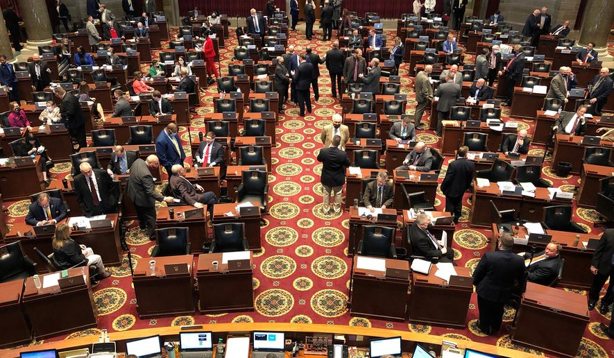 Members of the Missouri House gather in the chamber before the beginning of session on Wednesday, Feb. 3, 2021, in Jefferson City, Mo. The House chamber has no mask mandate and has not modified its seating during the coronavirus pandemic. The House canceled all work for a full week in January after a COVID-19 outbreak. (AP Photo/David A. Lieb)
