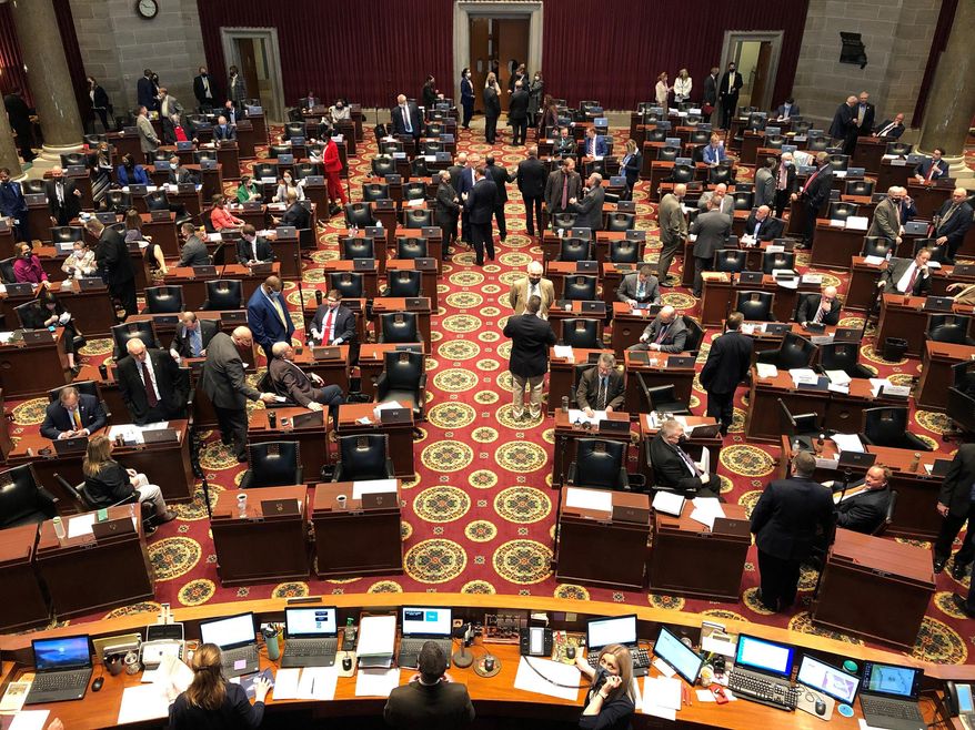 Members of the Missouri House gather in the chamber before the beginning of session on Wednesday, Feb. 3, 2021, in Jefferson City, Mo. The House chamber has no mask mandate and has not modified its seating during the coronavirus pandemic. The House canceled all work for a full week in January after a COVID-19 outbreak. (AP Photo/David A. Lieb)