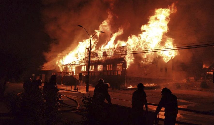 Firefighters work to fight a blaze at the mayor's office set on fire during a protest against the shooting of a street juggler killed by police during an identity check, in Panguipulli, Chile, Friday, Feb. 5, 2021. (Alicia Caceres/Aton Chile via AP)