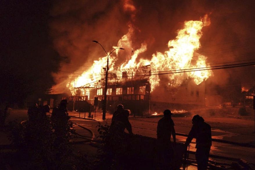 Firefighters work to fight a blaze at the mayor's office set on fire during a protest against the shooting of a street juggler killed by police during an identity check, in Panguipulli, Chile, Friday, Feb. 5, 2021. (Alicia Caceres/Aton Chile via AP)
