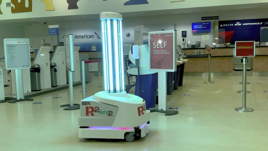 In this Tuesday, Feb. 2, 2021, photo provided by the Florida Keys News Bureau, an ultraviolet light-emitting robot rolls in front of check-in counters at Key West International Airport in Key West, Fla. On Friday, Feb. 5, 2021, the Florida Keys tourism council announced the winner of a contest to name the robot. "R2Key2" was submitted by Chelsea Atkins of Bat Cave, North Carolina. Key West was among the first airports in the United States to take delivery of the apparatus that is programmed to flood areas with UV light to kill COVID-19. (Steve Panariello/Florida Keys News Bureau via AP)