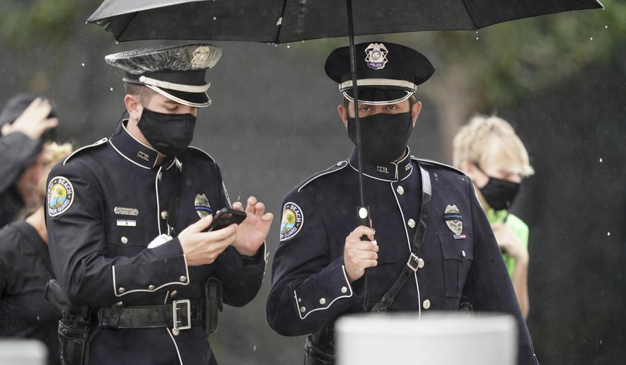 Members of the Delray Beach Police force arrive in the rain for a memorial service for FBI Special Agent Laura Schwartzenberger, Saturday, Feb. 6, 2021, in Miami Gardens, Fla. Schwartzenberger and Special Agent Daniel Alfin were killed while serving a warrant this week in Sunrise, Fla. (AP Photo/Hans Deryk)