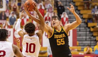 Indiana guard Rob Phinisee (10) and Iowa center Luka Garza (55) battle for the ball during the first half of an NCAA college basketball game, Sunday, Feb. 7, 2021, in Bloomington, Ind. (AP Photo/Doug McSchooler)