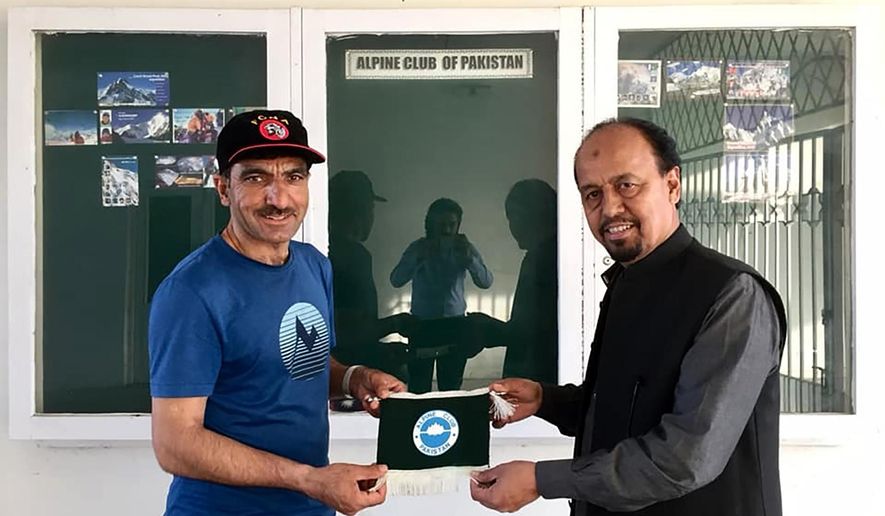 In this 2018 photo provided by Alpine Club of Pakistan shows, Pakistani mountaineer Ali Sadpara, left, receives a souvenir from Karrar Haider, a top official of Alpine Club of Pakistan, at his office in Islamabad, Pakistan. An aerial search mission is on to find three experienced climbers, Sadpara and his two companions, John Snorri and Juan Pablo Mohr, who lost contact with the base camp during their ascend on world&#39;s second top peak in northern Pakistan, official said Sunday, Feb. 7, 2021. (Alpine Club of Pakistan via AP)