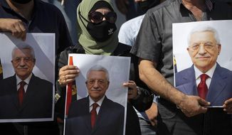 In this Sept. 27, 2020, file photo, Palestinians wearing protective face masks amid the coronavirus pandemic, hold pictures of Palestinian President Mahmoud Abbas during a rally to support Abbas, in the West Bank town of Tubas. President Abbas called for legislative elections on May 22 and presidential elections on July 31, 2021. (AP Photo/Majdi Mohammed, File)
