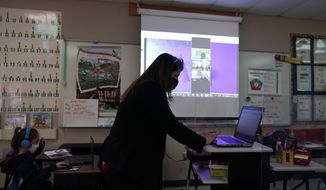 Wylona Rogers teaches students attending a class in-person as well as students attending virtually at Driggers Elementary School, Monday, Feb. 8, 2021, in San Antonio. After seeing two academic years thrown off course by the pandemic, school leaders around the country are planning for the possibility of more distance learning next fall at the start of yet another school year. (AP Photo/Eric Gay) **FILE**