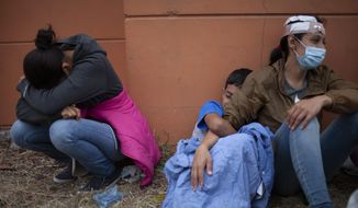 In this Jan. 17, 2021, photo, injured women, part of a Honduran migrant caravan in their bid to reach the U.S. border, weep as they sit on the side of a highway after clashing with Guatemalan police and soldiers in Vado Hondo, Guatemala, Guatemala. U.S. Federal law allows immigrants facing credible threats of persecution or violence in their home country to seek U.S. asylum. (AP Photo/Sandra Sebastian) **FILE**