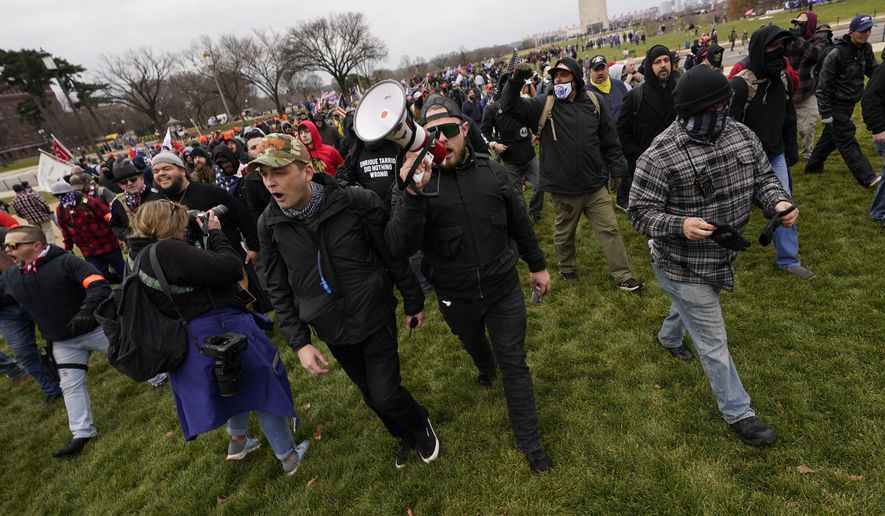 FILE - In this Wednesday, Jan. 6, 2021 file photo Ethan Nordean, with backward baseball hat and bullhorn, leads members of the far-right group Proud Boys in marching before the riot at the U.S. Capitol. Nordean, 30, of Auburn, Washington, has described himself as the sergeant-at-arms of the Seattle chapter of the Proud Boys. The Justice Department has charged him in U.S. District Court in Washington, D.C., with obstructing an official proceeding, aiding and abetting others who damaged federal property, and knowingly entering or remaining in a restricted building. He asked a judge Monday, Feb. 8, 2021, to release him from detention pending trial. (AP Photo/Carolyn Kaster,File)