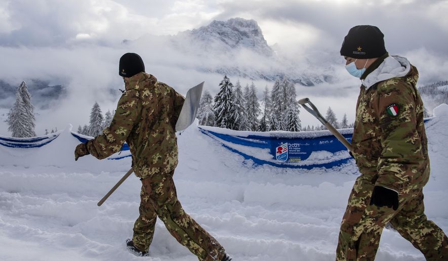 Italian soldiers clean fresh snow at the 2021 FIS Alpine Skiing World Championships in Cortina d'Ampezzo, Italy, Monday, February 8, 2021. A women's alpine combined race was canceled due to heavy snowfall, at the alpine ski World Championships. (Jean-Christophe Bott/Keystone via AP)