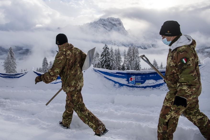Italian soldiers clean fresh snow at the 2021 FIS Alpine Skiing World Championships in Cortina d'Ampezzo, Italy, Monday, February 8, 2021. A women's alpine combined race was canceled due to heavy snowfall, at the alpine ski World Championships. (Jean-Christophe Bott/Keystone via AP)