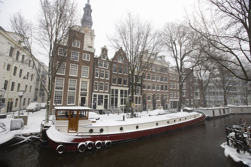 Snow covers a houseboat in Amsterdam, as snow and strong winds blanketed much of the Netherlands, Sunday, Feb. 7, 2021. (AP Photo/Peter Dejong)