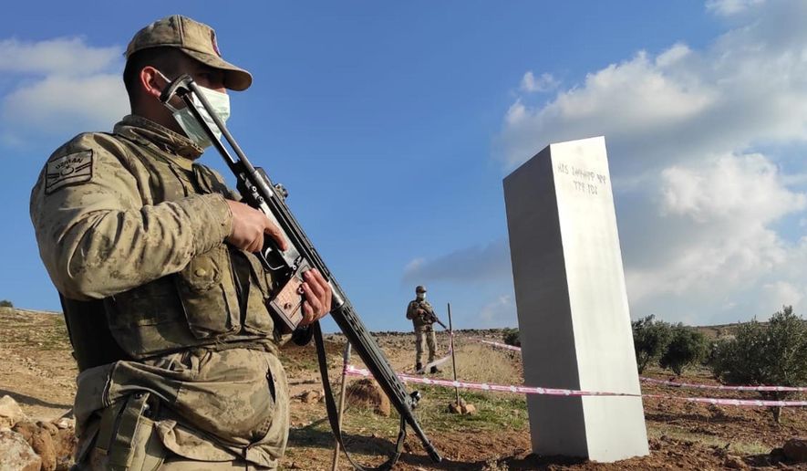 Turkish police officers guard a monolith, found on an open field near Sanliurfa, southeastern Turkey, Sunday, Feb. 7, 2021. The metal block was found by a farmer Friday in Sanliurfa province with old Turkic script that reads "Look at the sky, see the moon." The monolith, 3 meters high (about 10 feet), was discovered near UNESCO World Heritage site Gobeklitepe with its megalithic structures dating back to 10th millennium B.C. Turkish media reported Sunday that gendarmes were looking through CCTV footage and investigating vehicles that may have transported the monolith. Other mysterious monoliths have popped up and some have disappeared in numerous countries since 2020. (Bekir Seyhanli/IHA via AP)