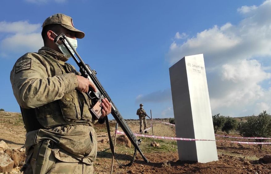 Turkish police officers guard a monolith, found on an open field near Sanliurfa, southeastern Turkey, Sunday, Feb. 7, 2021. The metal block was found by a farmer Friday in Sanliurfa province with old Turkic script that reads "Look at the sky, see the moon." The monolith, 3 meters high (about 10 feet), was discovered near UNESCO World Heritage site Gobeklitepe with its megalithic structures dating back to 10th millennium B.C. Turkish media reported Sunday that gendarmes were looking through CCTV footage and investigating vehicles that may have transported the monolith. Other mysterious monoliths have popped up and some have disappeared in numerous countries since 2020. (Bekir Seyhanli/IHA via AP)