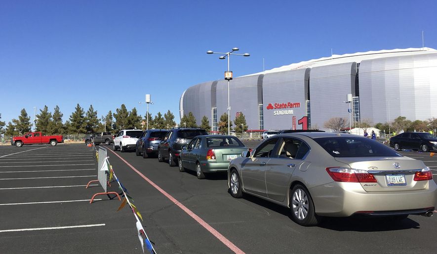 FILE - In this Jan. 11, 2021 fie photo drivers wait in line to get the COVID-19 vaccine in the parking lot of the State Farm Stadium in Glendale, Ariz. Arizona officials, who have pressed for more COVID-19 vaccines, got a chance to show the White House how quickly they could put them to use. President Joe Biden and Vice President Kamala Harris heaped praise Monday, Feb. 8, 2021, during a virtual tour of the state's first mass COVID-19 vaccination site at State Farm Stadium in Glendale. (AP Photo/Terry Tang, File)