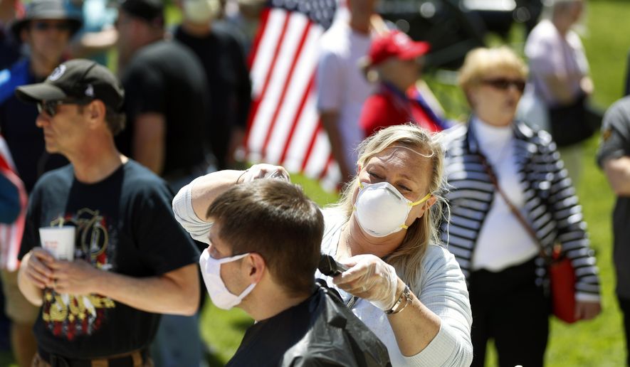 FILE — Brandi Bates gives Mike Greenbauer a free haircut at the State Capitol during a rally in Lansing, Mich., Wednesday, May 20, 2020. A judge dismissed disorderly conduct charges Monday against six hair stylists who were ticketed last spring during a protest at the Michigan Capitol. The women were cutting hair to protest Gov. Gretchen Whitmer's decision to keep barbershops and salons closed for nearly three months because of the coronavirus pandemic. (AP Photo/Paul Sancya, File)