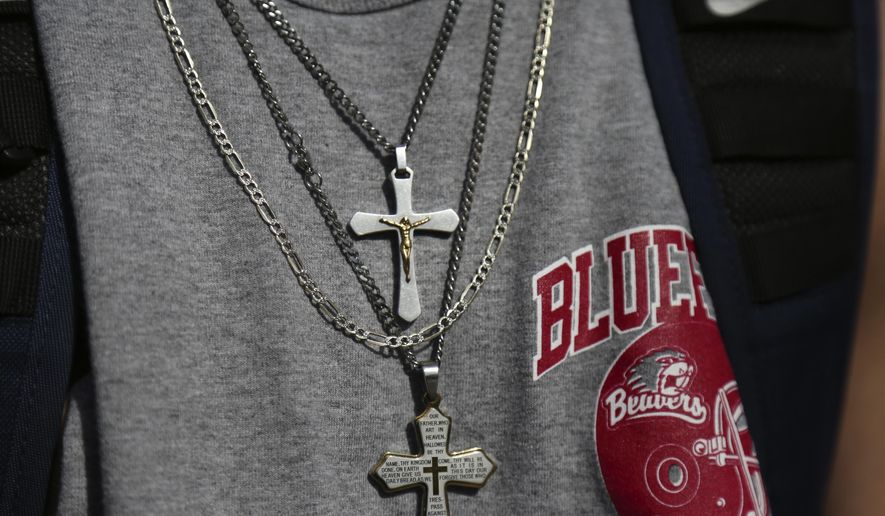 A student wears a pair of cross necklaces over a Bluefield High School football shirt while walking home in Bluefield, W.Va., on Tuesday, Jan. 24, 2021. (AP Photo/Jessie Wardarski) ** FILE **