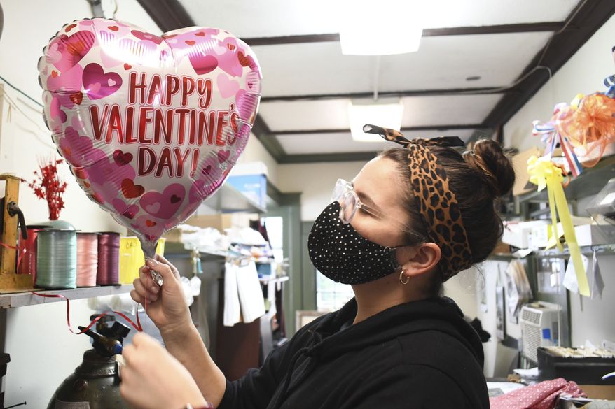 Carolyn Beaudreau blows up a helium balloon with Valentine's Day theme at Mount Williams Greenhouses in North Adams, Mass on Tuesday, Feb. 9, 2021, as area florists get ready for the busy Valentine's Day weekend. (Gillian Jones/The Berkshire Eagle via AP)