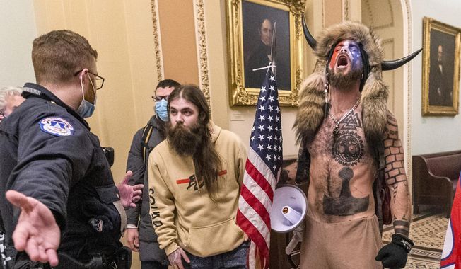 In this Wednesday, Jan. 6, 2021, photo, supporters of President Donald Trump, including Jacob Chansley, right with fur hat, are confronted by U.S. Capitol Police officers outside the Senate Chamber inside the Capitol in Washington. A judge ordered corrections authorities to provide organic food to an Arizona man who is accused of participating in the insurrection at the U.S. Capitol while sporting face paint, no shirt and a furry hat with horns.  (AP Photo/Manuel Balce Ceneta) **FILE**