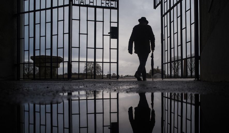 File - In this Sunday, Jan. 27, 2019 file photo a man walks through the gate of the Sachsenhausen Nazi death camp with the phrase &#x27;Arbeit macht frei&#x27; (work sets you free) during International Holocaust Remembrance Day in Oranienburg, about 30 kilometers (18 miles), north of Berlin, Germany. German prosecutors say they have charged a 100-year-old man with 3,518 counts of accessory to murder on allegations he served as an SS guard at the Nazis’ Sachsenhausen concentration camp on the outskirts of Berlin. (AP Photo/Markus Schreiber, file)