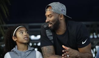 In this July 26, 2018, file photo, former Los Angeles Laker Kobe Bryant and his daughter Gianna watch the U.S. national championships swimming meet in Irvine, Calif. Federal safety officials are expected to vote Tuesday, Feb. 9, 2021, on what likely caused the helicopter carrying Kobe Bryant, his 13-year-old daughter and seven others to crash into a Southern California hillside last year, killing all aboard. (AP Photo/Chris Carlson, file) **FILE**