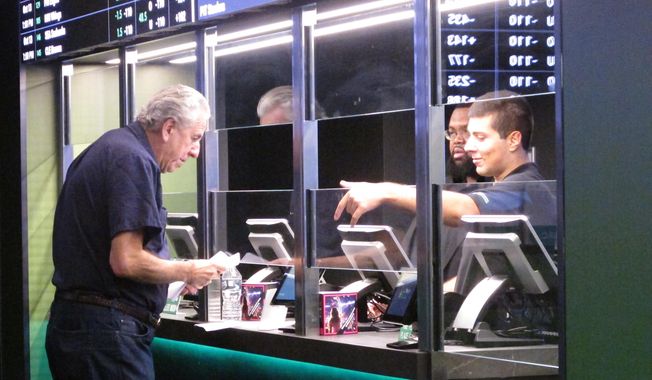 In this Oct. 8, 2019, file photo, a man makes a sports bet at Resorts casino in Atlantic City, N.J. Sports books say the blitz of advertising they launched in the run up to the 2021 Super Bowl, while costly, paid off in terms of attracting new customers to the fast-growing legal sports betting industry in the U.S. (AP Photo/Wayne Parry, File) **FILE**