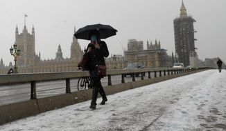 A woman walks over Westminster Bridge as temperatures dropped below freezing during the third coronavirus lockdown in London, Tuesday, Feb. 9, 2021. (AP Photo/Kirsty Wigglesworth)